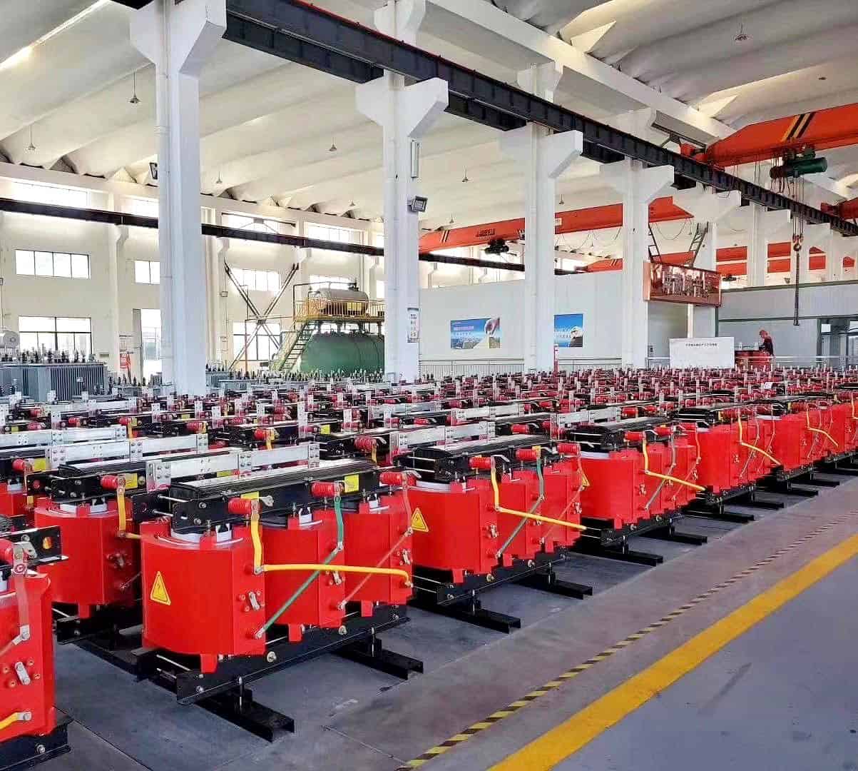 Interior of factory with rows of red dry-type transformers lined up on the production floor